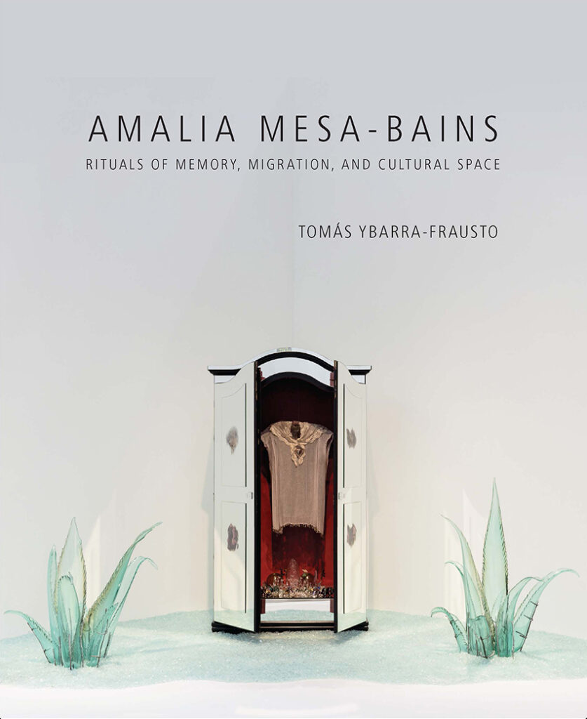 Amalia Mesa-Bains gray book cover with an installation with a mirrored armoire in the center and green glass plants on each side.