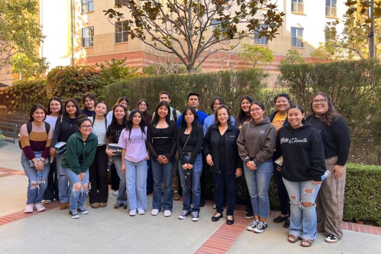 A group of about twenty students posing together outdoors on the UCLA campus.