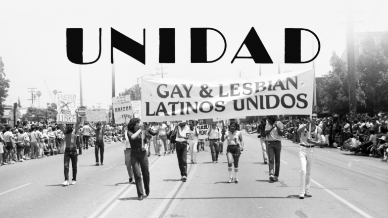 Black and white Unidad film still of marchers carrying a "Gay & Lesbian Latinos Unidos" banner during a parade.