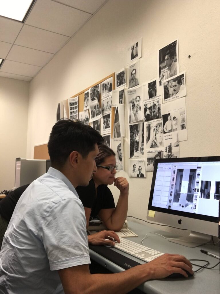 Two people seated at a computer at the CSRC, viewing materials on a computer, with images of historical photographs displayed on the wall.