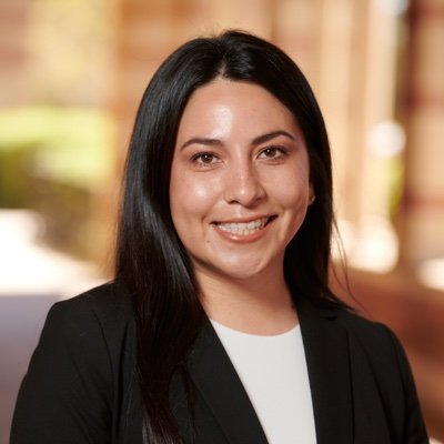 Ann Marie Hernandez smiling in a black blazer, with straight dark hair and a blurred indoor background.