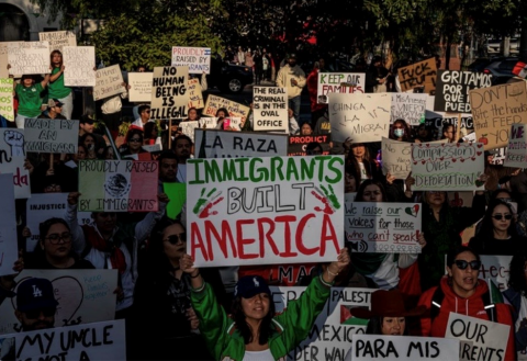 Photograph of a large crowd of protesters holding signs supporting immigrants and opposing deportation, one reading "Immigrants Built America."